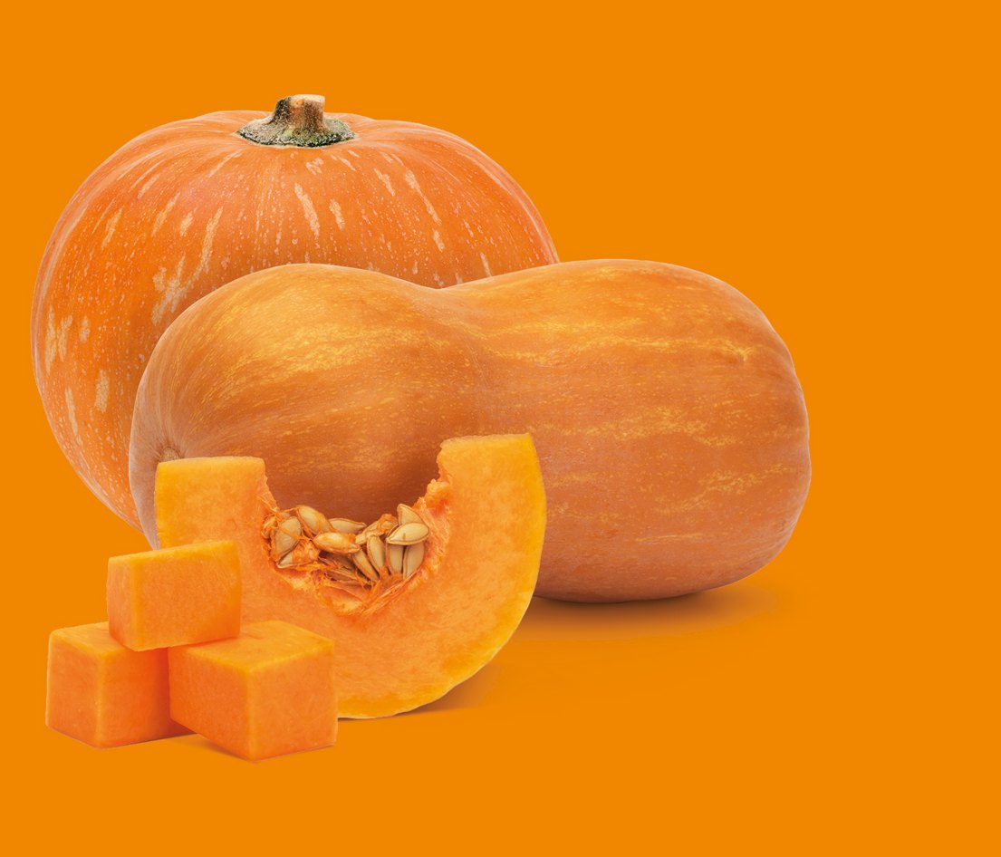 Calabazas enteras y taquitos de calabaza troceada sobre fondo naranja