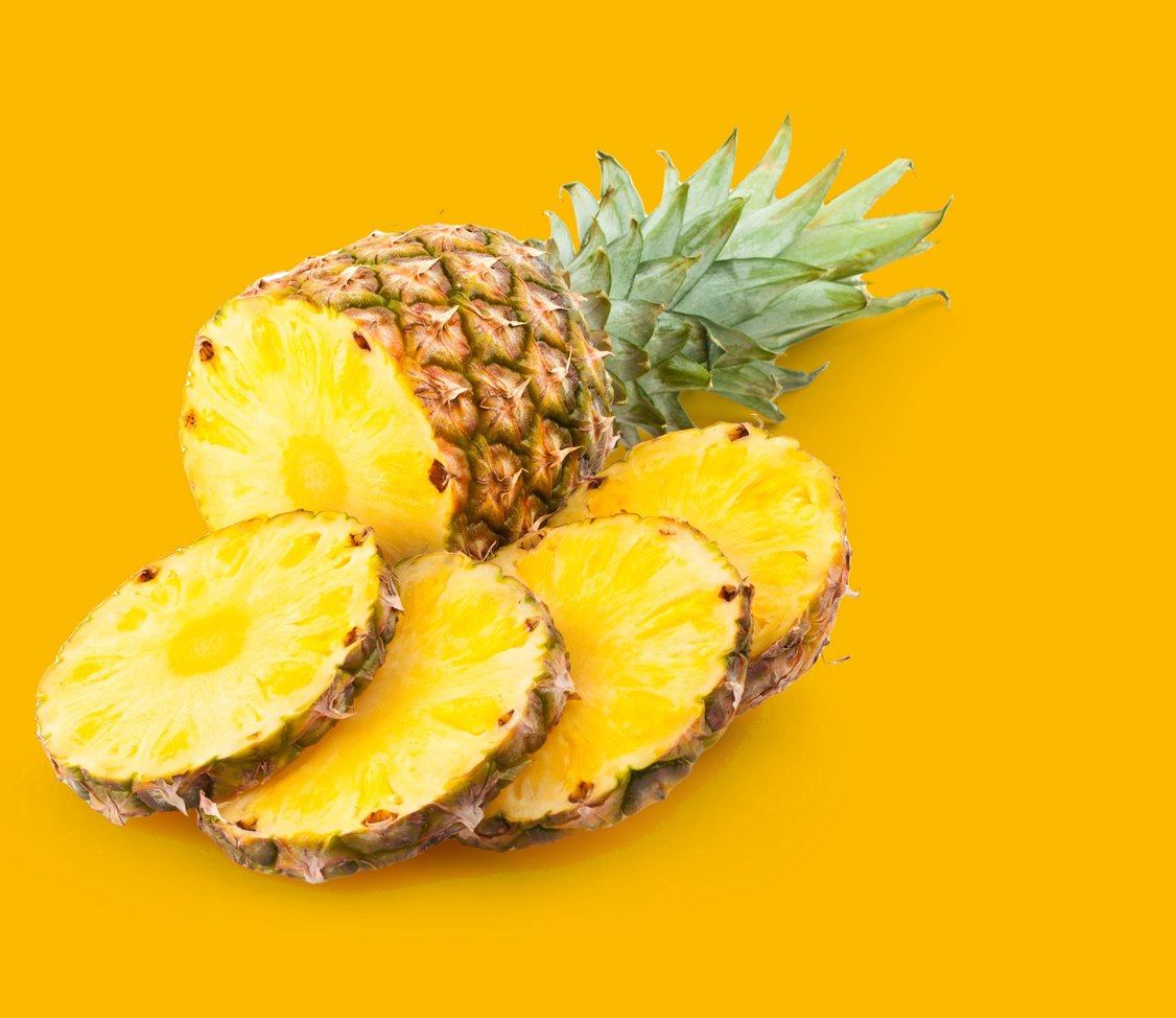 Piña entera con hojas y trozos de piña troceada, sobre fondo amarillo